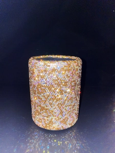 Close-up of a sparkling gold cylindrical makeup brush holder with multicolored rhinestones