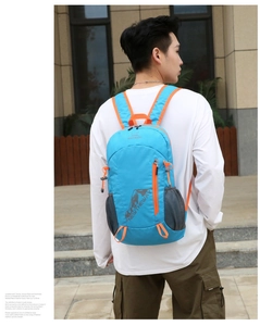 Detail of blue foldable outdoor backpack with orange zippers and mesh side pockets