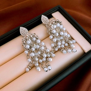 Close-up of vintage rhinestone fan earrings with white pearl tassels in a jewelry box