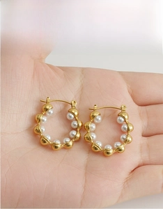 Detail of 18k gold plated hoop earrings with bubble texture and embedded white pearls