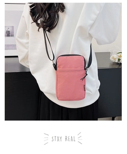 Pink corduroy crossbody phone bag featuring a vertical design and black nylon strap