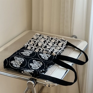 Detail shot of vintage butterfly embroidery and floral patterns on black canvas mini bags