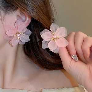 Pink acrylic flower earrings with pearl stamen and gold accents on female model