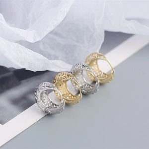 Detailed view of hollow patterned hoop earrings in polished gold and silver finishes