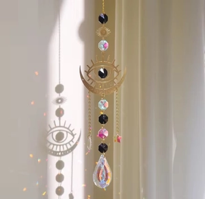 Detail of moon suncatcher with evil eye design and multifaceted crystals reflecting rainbows