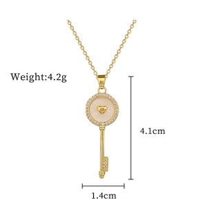 Detail of gold shell key pendant with heart-shaped inlay and dimensions of 4.1cm by 1.4cm