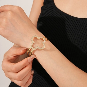 Dettaglio del bracciale a quadrifoglio dorato con zirconi incastonati sul polso di una modella