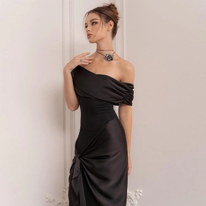 Detail of elegant black satin one-shoulder dress with draped waist and pleated fabric