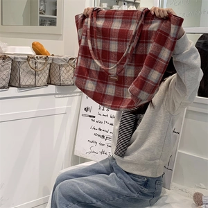 Détail d'un grand sac cabas à carreaux tartans rouge et gris avec étiquette en cuir