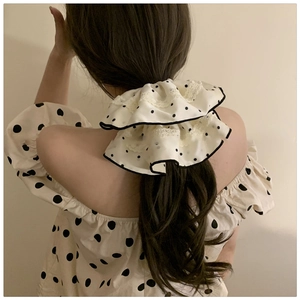 Close-up of retro polka dot satin scrunchie with delicate lace trim on hair