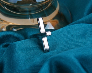 Detailed close-up of a silver S925 cross ring on elegant teal velvet fabric background