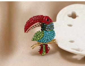 Detailed close-up of a vibrant parrot brooch with colorful rhinestones on golden branch