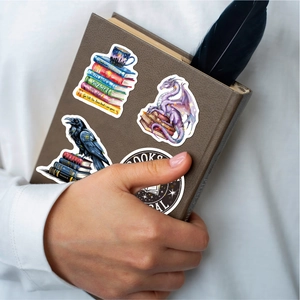 Close-up of holographic stickers on a brown leather notebook held by hand
