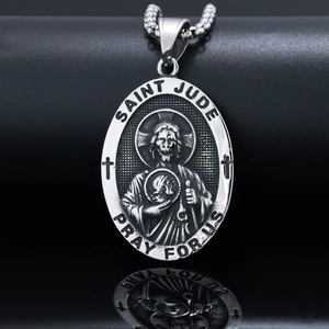 Macro shot of silver Saint Jude oval pendant with religious relief and prayer engraving