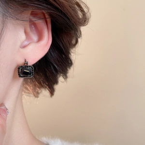 Close-up of black square gemstone earrings with matching halo on model's ear