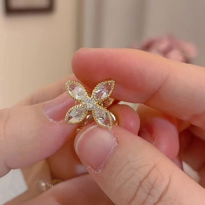 Détail de boucle d'oreille fleur vintage dorée avec zircons et bordure en métal perlé