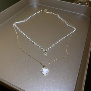 Detail of French double layer gold necklace featuring a heart pendant and small pearls