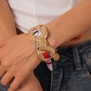 Detail of gold metal textured cuff bracelet with woven colorful silk scarf wrap