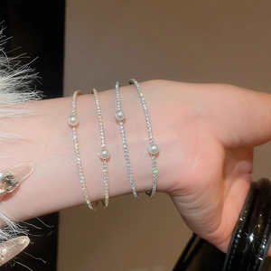 Detailed view of layered bangle bracelets featuring sparkling zircons and white pearls