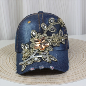 Detailed close-up of blue denim baseball cap featuring 3D floral embroidery and rhinestones