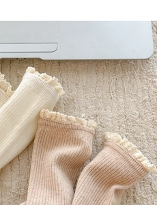Detail of Japanese style lace trim socks in cream and brown on a soft rug