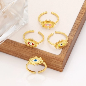 Detailed macro view of four adjustable gold-plated evil eye rings with colorful enamel centers