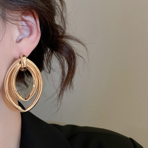 Gros plan de boucles d'oreilles ovales dorées entrelacées montrant la texture du métal poli
