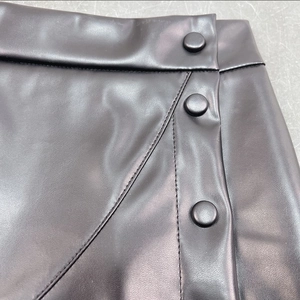Detailed view of black faux leather skirt waist featuring reinforced stitching and buttons