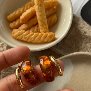 Detailed close-up of C-shaped amber resin earrings with elegant golden metal trim