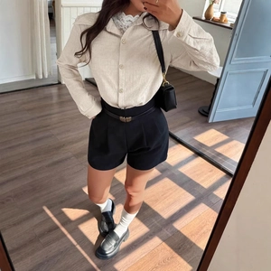 Detailed view of beige textured long sleeve shirt paired with high waist black shorts