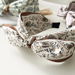 Close-up of paisley print fabric headband with layered bow detail and brown piping