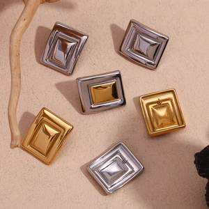 Macro shot of geometric rectangular stud earrings in gold and silver on stone