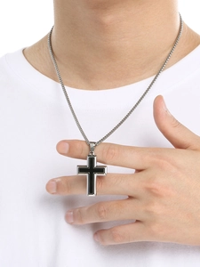 Gros plan d'un pendentif croix bicolore noir et argent sur une chaîne maille vénitienne