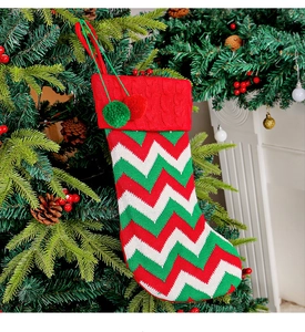 Detail of a knit Christmas stocking with colorful wave patterns hanging on a tree