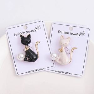 Detailed close-up of cat brooches with pearl accents and glossy enamel finish