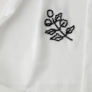 White urban commuter shirt featuring elegant hand-beaded black leaf embroidery details