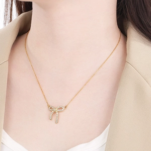 Elegant gold bow necklace with sparkling zircon pendant worn by a professional woman