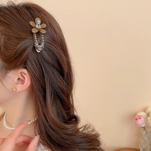Detail of a brown acrylic flower hair clip with rhinestones worn on long brown hair