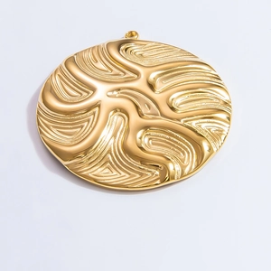 Detail of round golden pendant featuring abstract ripple relief texture on metal surface