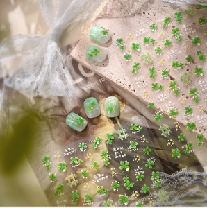 Macro detail of clover nail art stickers with Japanese text on soft green manicured tips