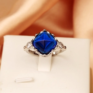 Macro view of blue sugarloaf sapphire ring with silver band on orange satin