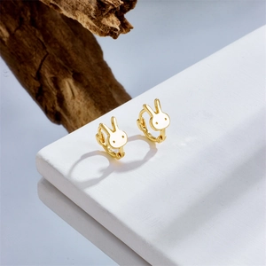 Elegant gold rabbit hoop earrings displayed on a white marble stone with wooden accents