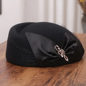 Detail of vintage wool hat featuring large satin bow, rhinestone brooch, and elegant mesh veil