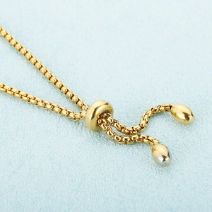 Gold plated snake chain bracelet with adjustable slide clasp on a blue background