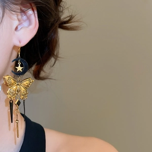 Détail de boucles d'oreilles lune papillon rétro avec longs pompons portées par un mannequin