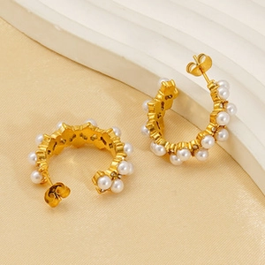 Close-up of golden C-shaped hoop earrings featuring neat rows of white pearls