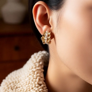 Close-up of 14k gold plated C-shape pearl earrings worn with an autumn knit sweater