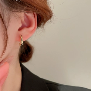 Detailed view of polished gold C-shape stud earrings on ear for a minimalist look