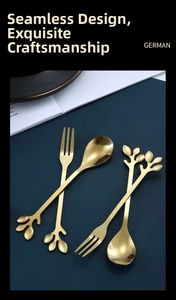 Macro shot of gold leaf-shaped stainless steel dessert cutlery set on dark background