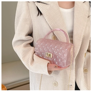 Close-up of pink jelly crossbody bag with quilted texture and beaded handle on a beige blazer
